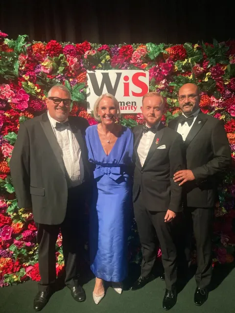 Four members of the GCG team in evening dress in front of the flower wall at the Women in Security Awards